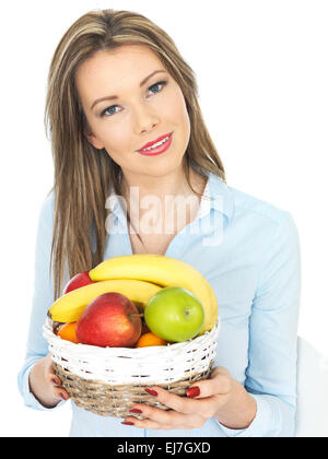 Fiducioso felice giovane donna in possesso di un paniere di freschi maturi Sano frutta mista isolata contro uno sfondo bianco con un tracciato di ritaglio e spazio di copia Foto Stock