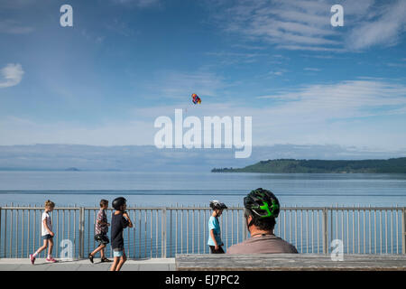 Uomo con i bambini del ciclo di indossare i caschi di sicurezza lungo il marciapiede accanto al Lago Taupo, Nuova Zelanda. Foto Stock