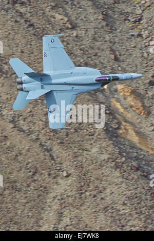 Close up di un US Navy F/A-18E Super Hornet jet fighter Banking ripidamente in un canyon del deserto. Foto Stock