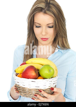 Fiducioso felice giovane donna in possesso di un paniere di freschi maturi Sano frutta mista isolata contro uno sfondo bianco con un tracciato di ritaglio e spazio di copia Foto Stock