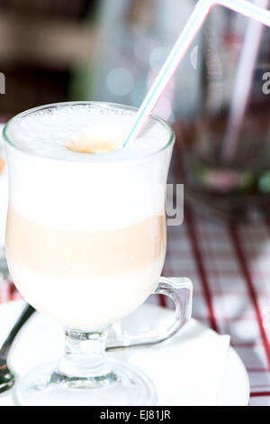Layered cappuccino in un vetro trasparente mug e paglia Foto Stock