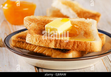 Fette di pane tostato fresco marmellata di colore arancione su sfondo di legno . Foto Stock