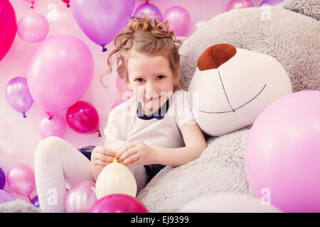 Ragazza sorridente si siede poggiando su big Teddy bear Foto Stock