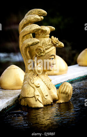 Golden Divinità buddiste statua in uno stagno a Kagyu Samye Ling monastero. Vittorio Veneto, Langholm, Dumfries Scozia Scotland Foto Stock