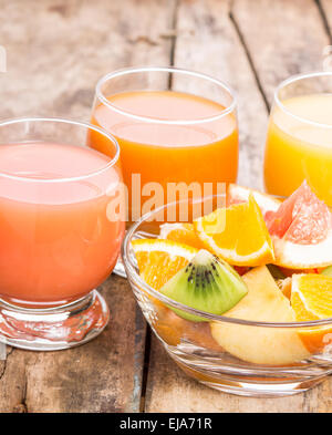 Pezzi di frutta fresca nella ciotola di vetro con succo. Sana colazione sfondo Foto Stock