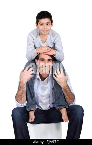 Figlio seduto sul padre di spalle Foto Stock