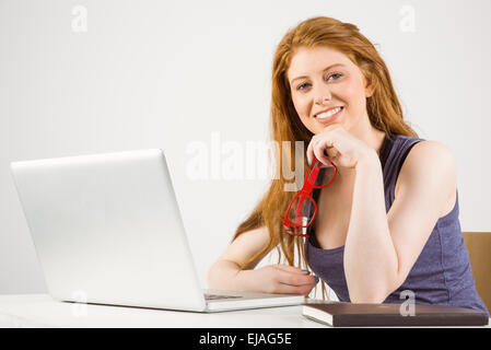 Pretty redhead lavorando sul computer portatile Foto Stock