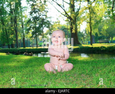 Little Boy sedersi su erba verde Foto Stock