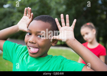 Carino piccolo ragazzo rendendo silly volti al di fuori Foto Stock