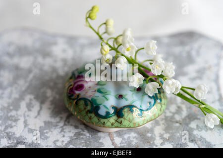 Il giglio della valle dei fiori (convallaria majalis) con dipinto a mano il coperchio del recipiente Foto Stock