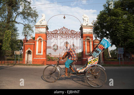 In rickshaw rider su trike al di fuori di porte di Cooch Behar Palace, chiamato anche il Giubileo Victor Palace, nel Bengala occidentale, India Foto Stock