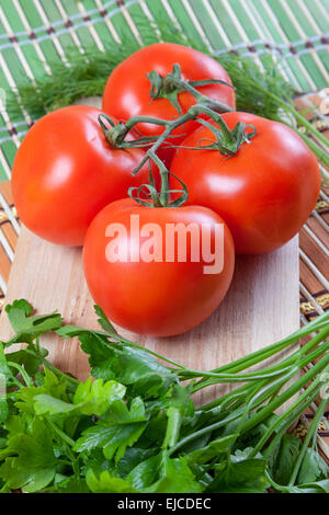 Pomodori sul tavolo con aneto e prezzemolo Foto Stock