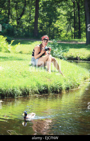 Una donna vintage tenendo la foto in un parco Foto Stock