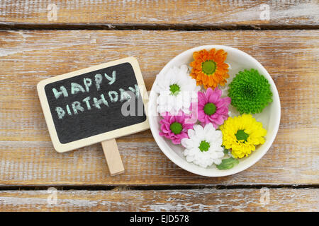 Buon compleanno scritto su mini blackboard e coloratissimi fiori Santini Foto Stock