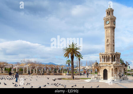 Izmir, Turchia - 12 Febbraio 2015: colombe e camminare la gente comune sulla piazza Konak vicino alla storica torre dell'orologio Foto Stock