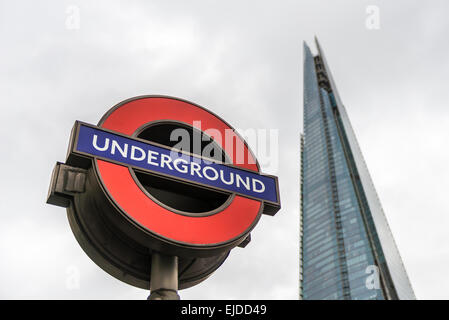 Una stazione della metropolitana di Londra segno mostrato con la Shard de-focalizzato in background Foto Stock