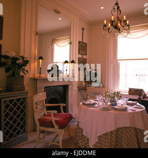 Lampadario illuminato sopra tavola circolare fissato per la cena in novanta sala da pranzo progettata da Gerard Conway Foto Stock