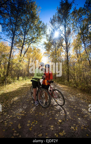 Due persone con la mountain bike, prendendo un riposo su un percorso avente un drink. Foto Stock