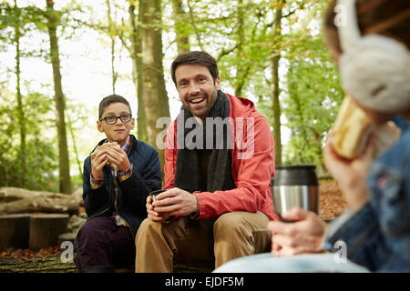 Boschi di faggio in autunno. Tre persone e un padre e due figli aventi un picnic. Foto Stock