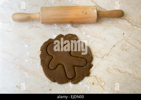 Perno di rotolamento sul bancone cucina con pasta laminata e tagliata fuori gingerbread man forma Foto Stock