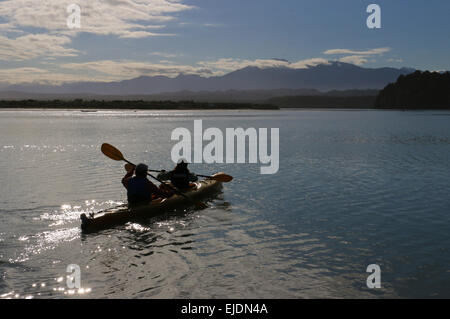 Kayakers Okarito Lagoon in Nuova Zelanda con il Sud delle Alpi montagne sullo sfondo Foto Stock