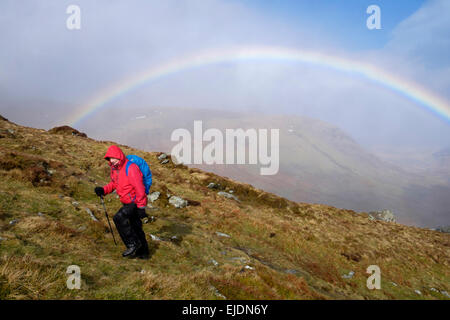 Escursionista escursionismo in salita in condizioni di bagnato con un arcobaleno sulla penna yr Helgi Du Carneddau nelle montagne del Parco Nazionale di Snowdonia, Galles del Nord, Regno Unito Foto Stock