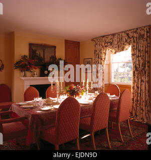 Rosa imbottiti in stile gotico sedie a tavola insieme per il pranzo nel paese sala da pranzo con tende dai motivi floreali in corrispondenza della finestra Foto Stock