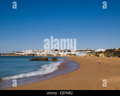 Persona che cammina da sola su una spiaggia deserta di inverno in Albufeira, Algarve, PORTOGALLO Foto Stock