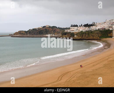 Giovane camminare da solo su una spiaggia deserta di inverno in Albufeira, Algarve, PORTOGALLO Foto Stock