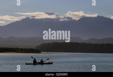 Kayakers Okarito Lagoon in Nuova Zelanda con il Sud delle Alpi montagne sullo sfondo Foto Stock