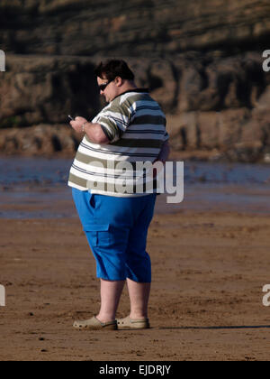 Uomo obesi in spiaggia, Bude, Cornwall, Regno Unito Foto Stock