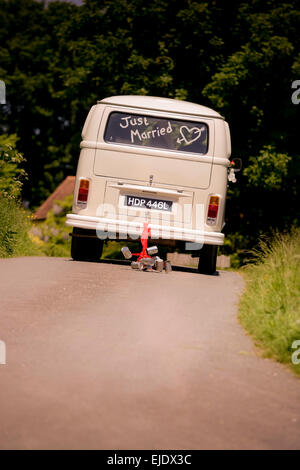 Volkswagen Camper autobus con appena sposato nella finestra di essere guidato via con lattine legate al paraurti posteriore. Foto Stock