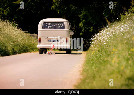 Volkswagen Camper autobus con appena sposato nella finestra di essere guidato via con lattine legate al paraurti posteriore. Foto Stock
