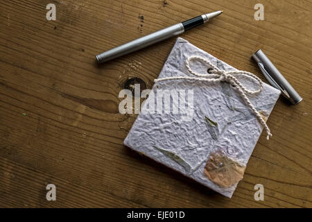 Diario di vecchi ricordi con una penna su un tavolo di legno. Elaborazione vintage. Foto Stock