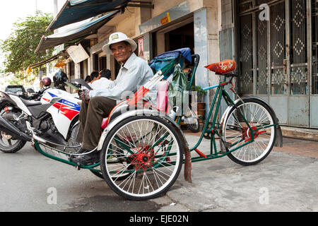 In rickshaw uomo in attesa per i clienti in Phnom Penh in Cambogia, in Asia. Foto Stock