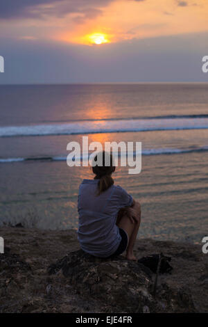 Donna guarda al tramonto nell'oceano. Foto Stock