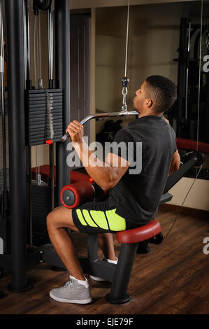 Giovane uomo facendo lats pull-down allenamento Foto Stock