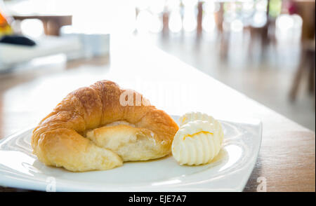 Il croissant e il burro nel piatto Foto Stock