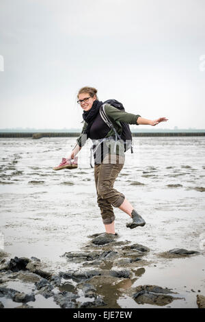 Giovane donna passeggiando per le velme del mare di Wadden (Wattenmeer) a bassa marea Foto Stock