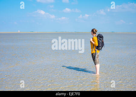 Giovane donna a piedi attraverso il mare di Wadden (Wattenmeer) a bassa marea Foto Stock