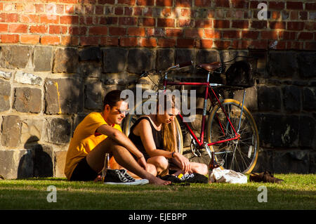I ciclisti in appoggio di fronte in mattoni e pietra blu edificio, Fitzroy, Victoria, Australia Foto Stock