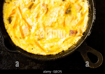 Uova strapazzate con prosciutto e carote in padella. Vista da vicino Foto Stock