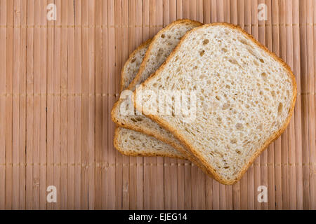 Fette di pane bianco su una tovaglia in legno, vista dall'alto Foto Stock