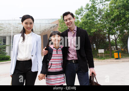 Una famiglia di tre nell'ingresso della scuola Foto Stock