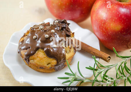 Deliziosi muffin al cioccolato in piedi su una piastra r con due mele in background Foto Stock