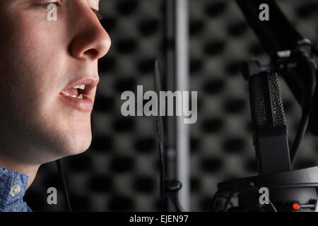 Uomo in studio di registrazione parlando nel microfono Foto Stock