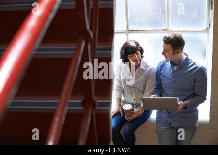 Due imprenditori aventi riunione informale sulle scale di Office Foto Stock