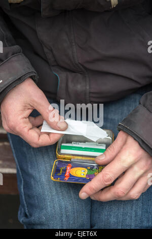 Un uomo di laminazione di un giunto usando felice Joker, un legale alta Foto Stock