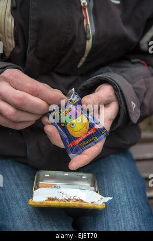 Un uomo di laminazione di un giunto usando felice Joker, un legale alta Foto Stock