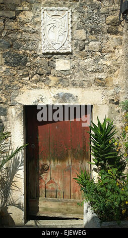 Antique House ingresso nelle zone rurali la Croazia, Dalmazia, porta in legno rivestiti in pietra bianca architrave in marmo con stemma Foto Stock
